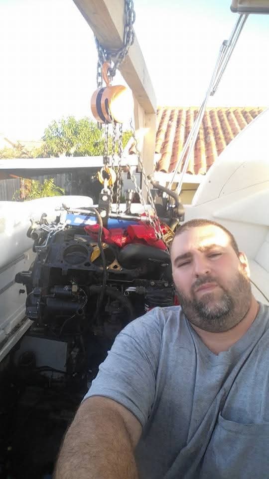Selfie with an engine hanging from a chain hoist