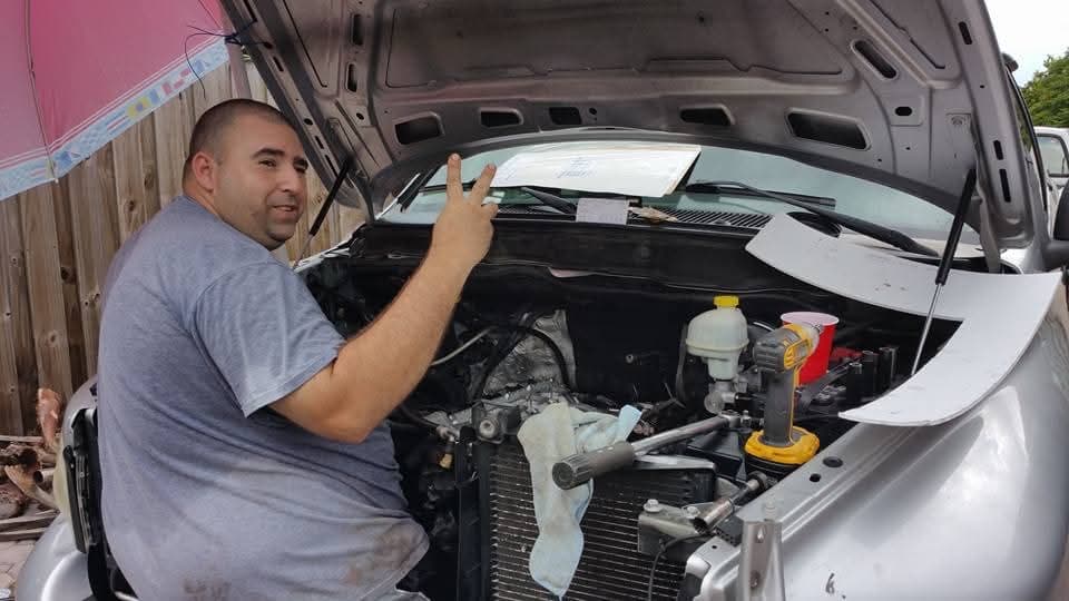 Peace sign from under the hood of a silver truck
